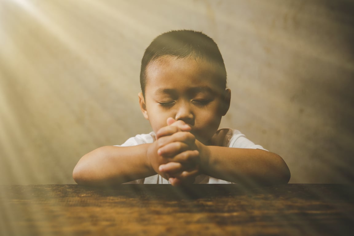 Little boy praying to God with hands held together